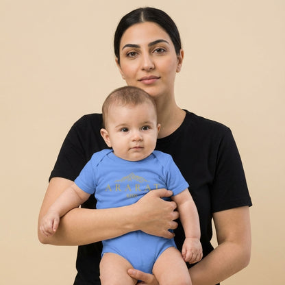 Woman holding a baby wearing a blue onesie with text on a beige background. Anarani Art Ararat Club Onesie.