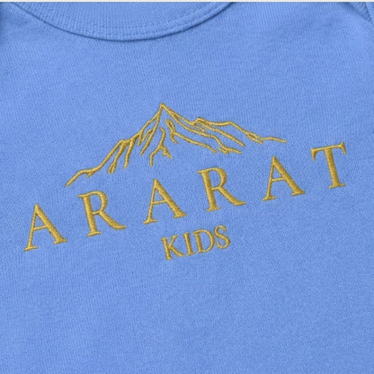 Blue baby onesie with gold 'Ararat Kids' text and mountain design on a beige background