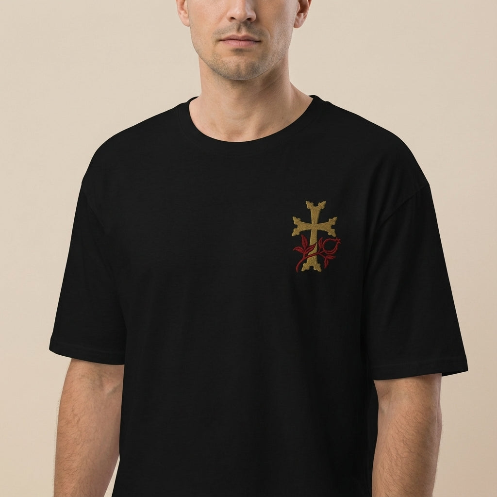 Man wearing a black t-shirt with a gold and red emblem on a beige background