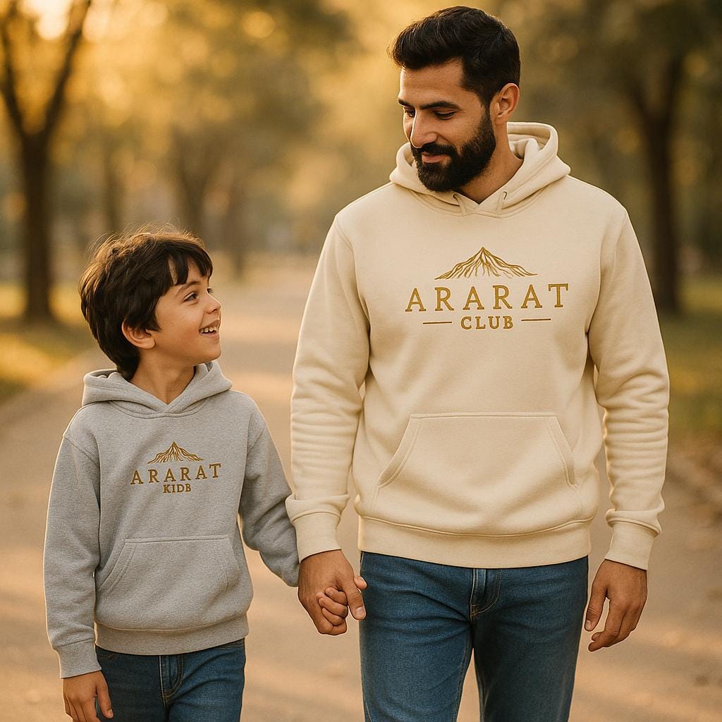 A father and son walking together, both wearing matching "ARARAT CLUB" hoodies, with the father smiling and looking down at his son.